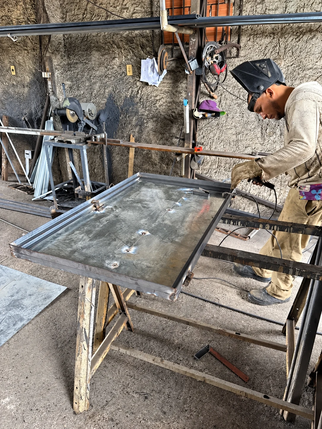 Trabalho em oficina na fabricação e montagem da porta metálica de proteção.